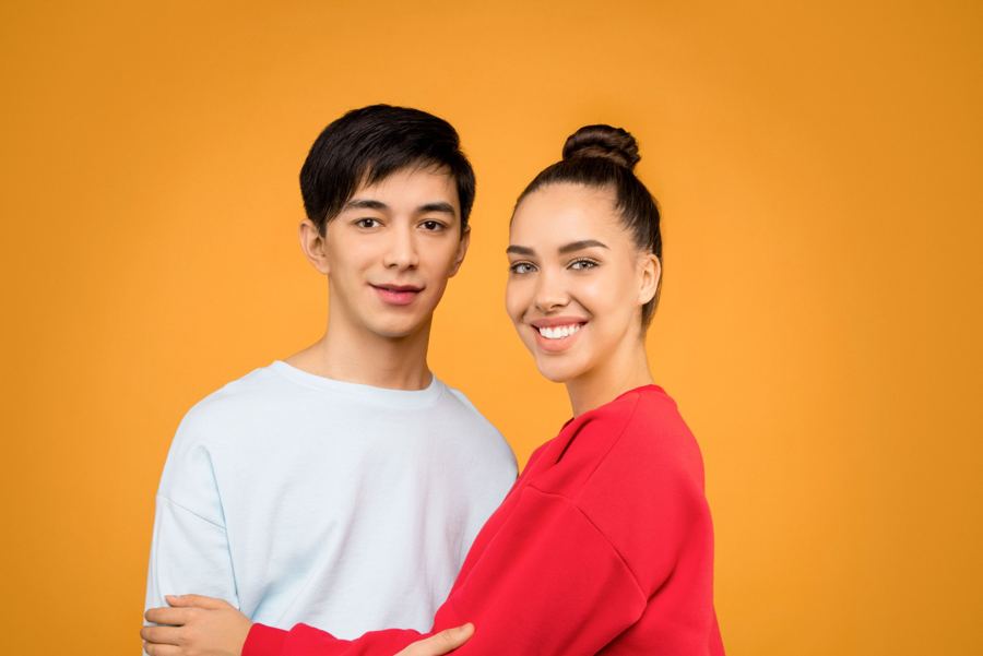 A smiling couple against an orange background